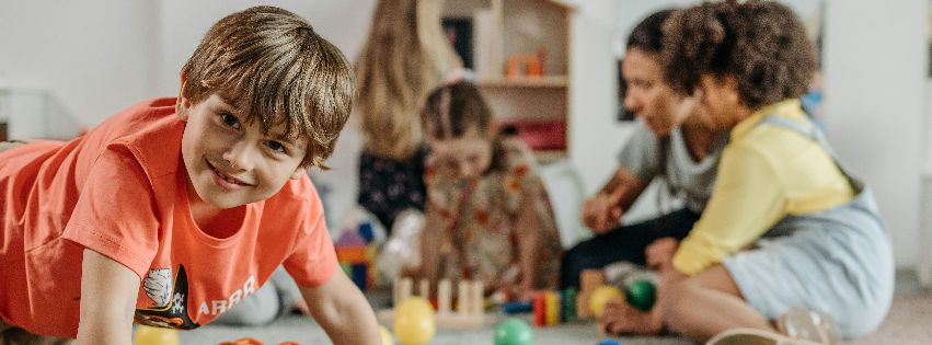 Junge spielt in einer Kindertagesstätte zusammen mit anderen Kindern