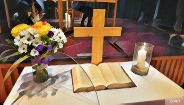 Offene Bibel, Kreuz, Blumenstrauß und Kerze auf weißem Tisch.