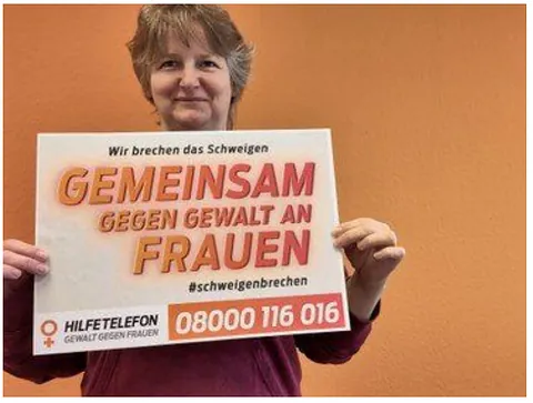 Frau hält Plakat gegen Gewalt an Frauen.