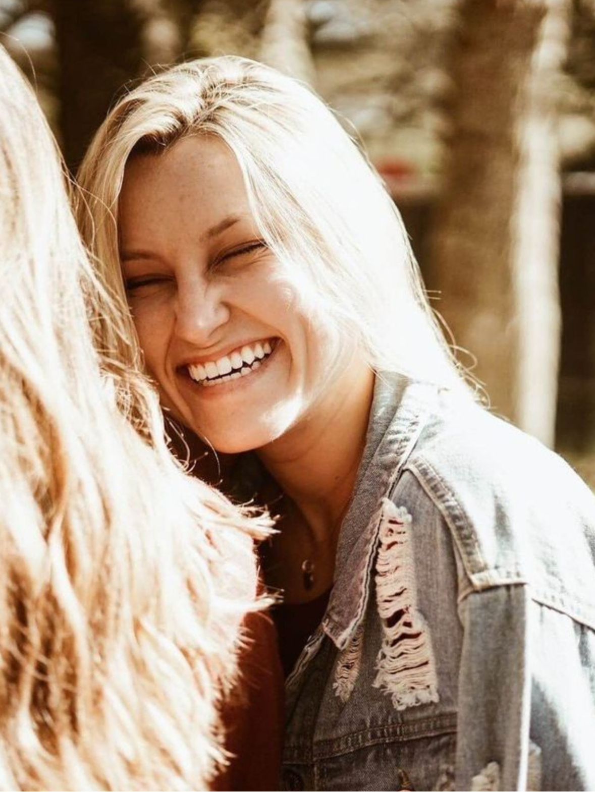 Lachende blonde Frau in Jeansjacke.