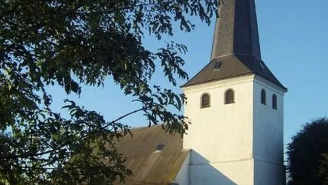 Weißer Kirchturm mit spitzem Dach.
