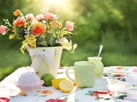 Blumenstrauß, Tasse und Zitronen auf einem Tisch.
